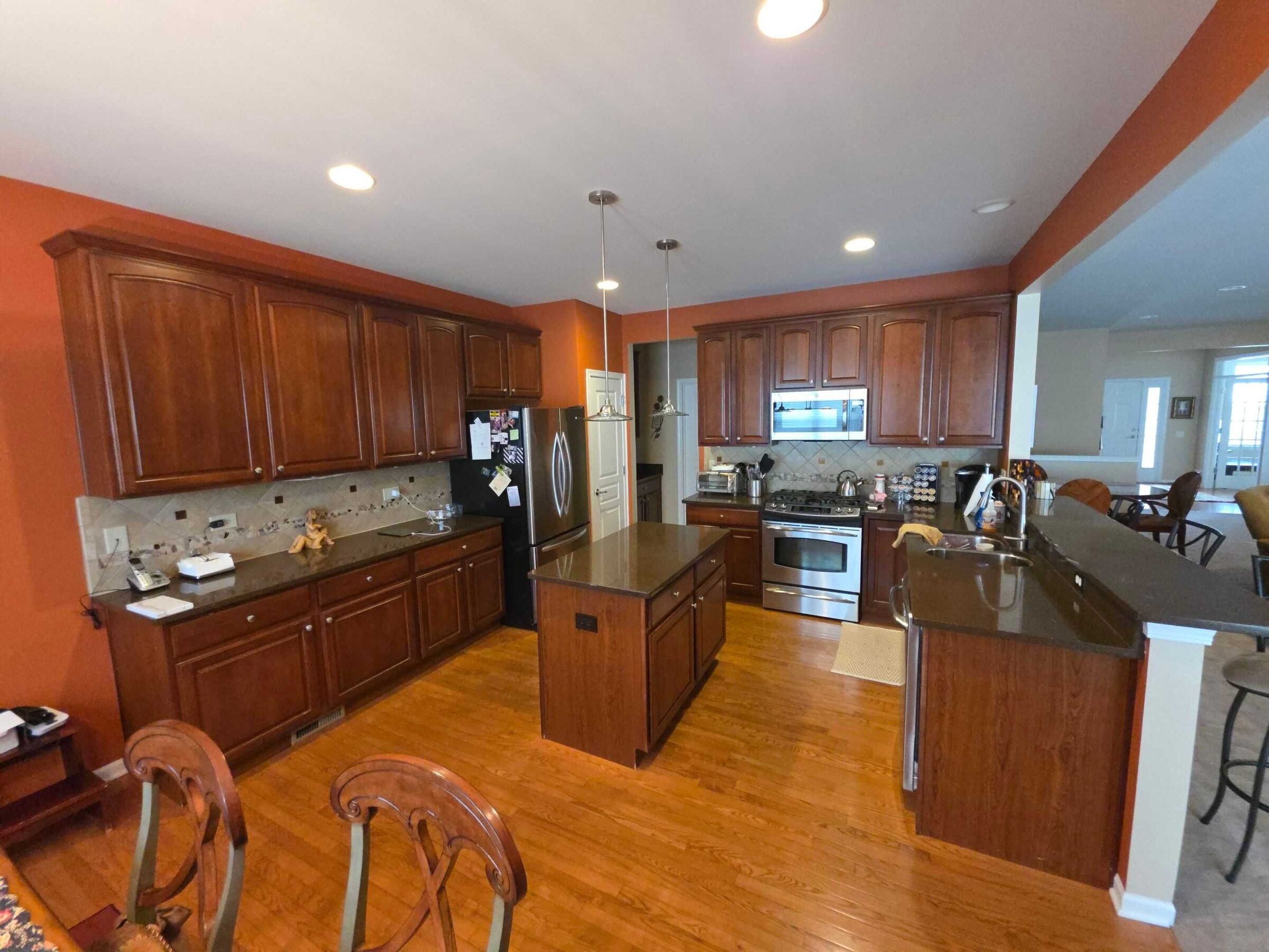 The same kitchen before, with dull brown granite on the island and peninsula and terracotta walls