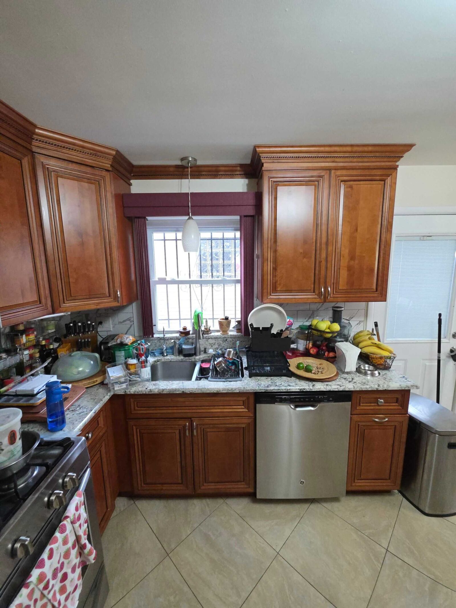 The old granite at the sink, crowded with dishes, fruit and a dish rack