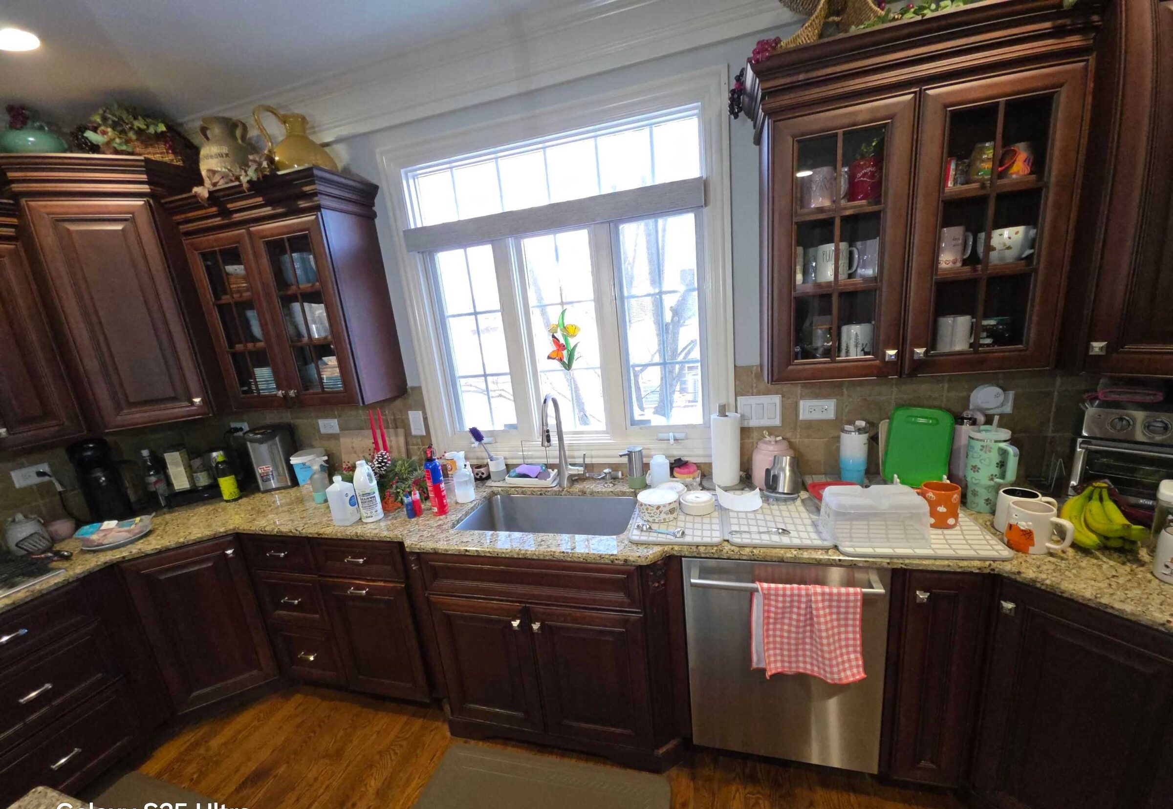 The old beige granite counter at the sink run, crowded with everyday kitchen clutter