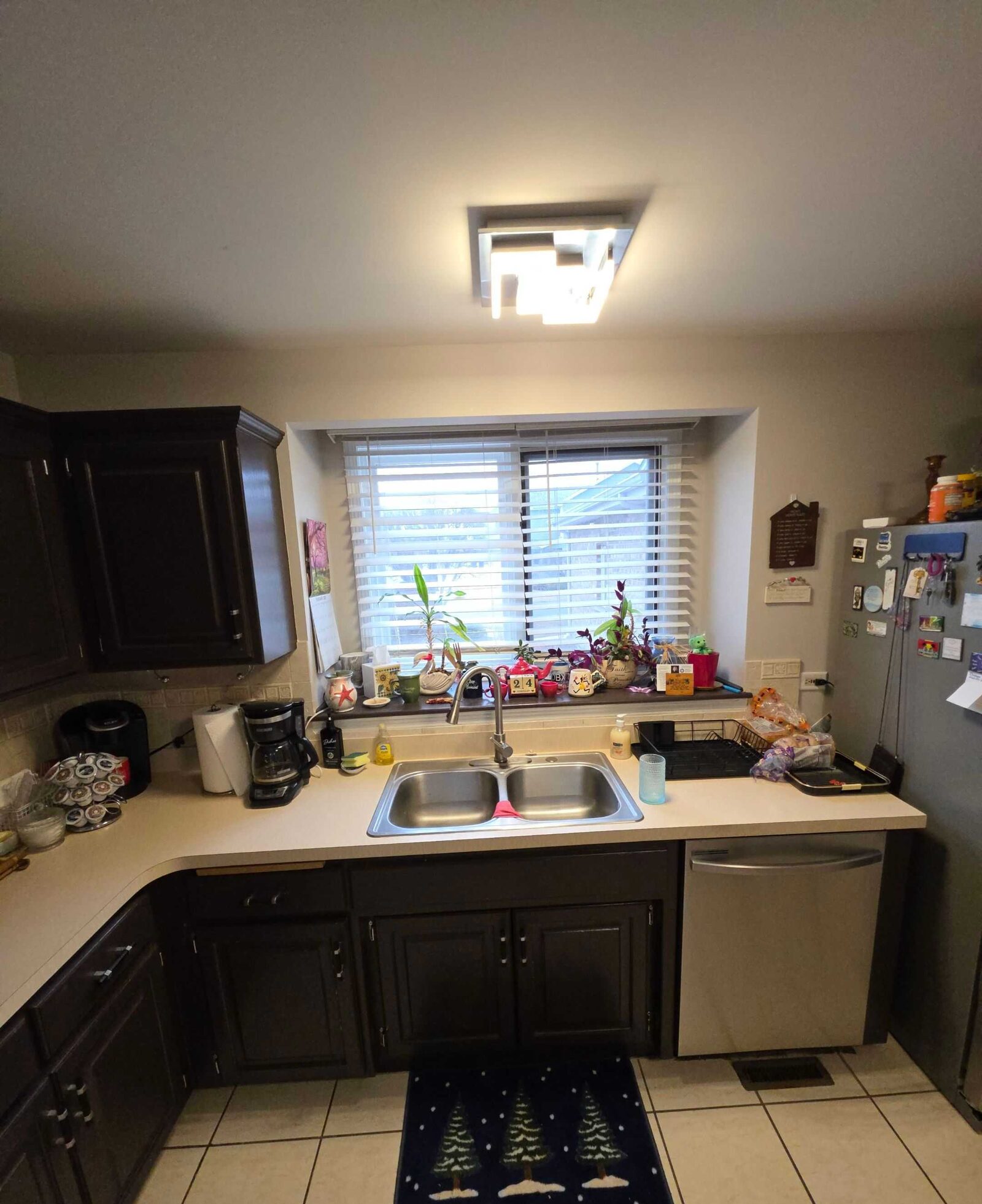 The old beige laminate at the sink, a coffee maker and bottles along the window ledge