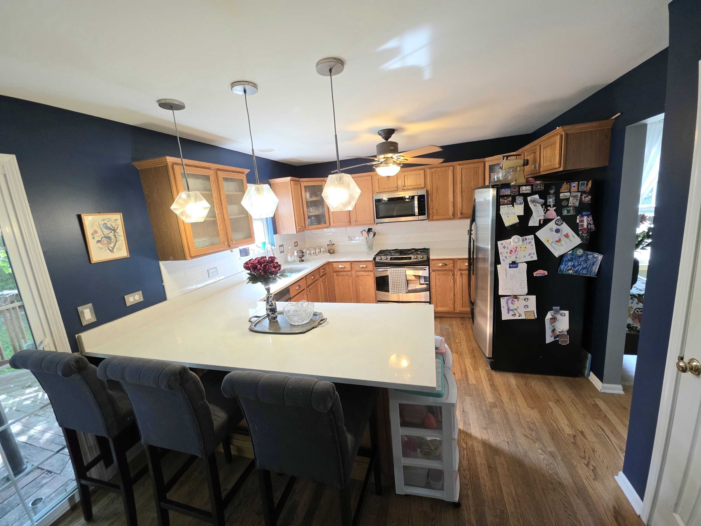 Finished white quartz peninsula seating four, oak cabinets and deep navy walls behind