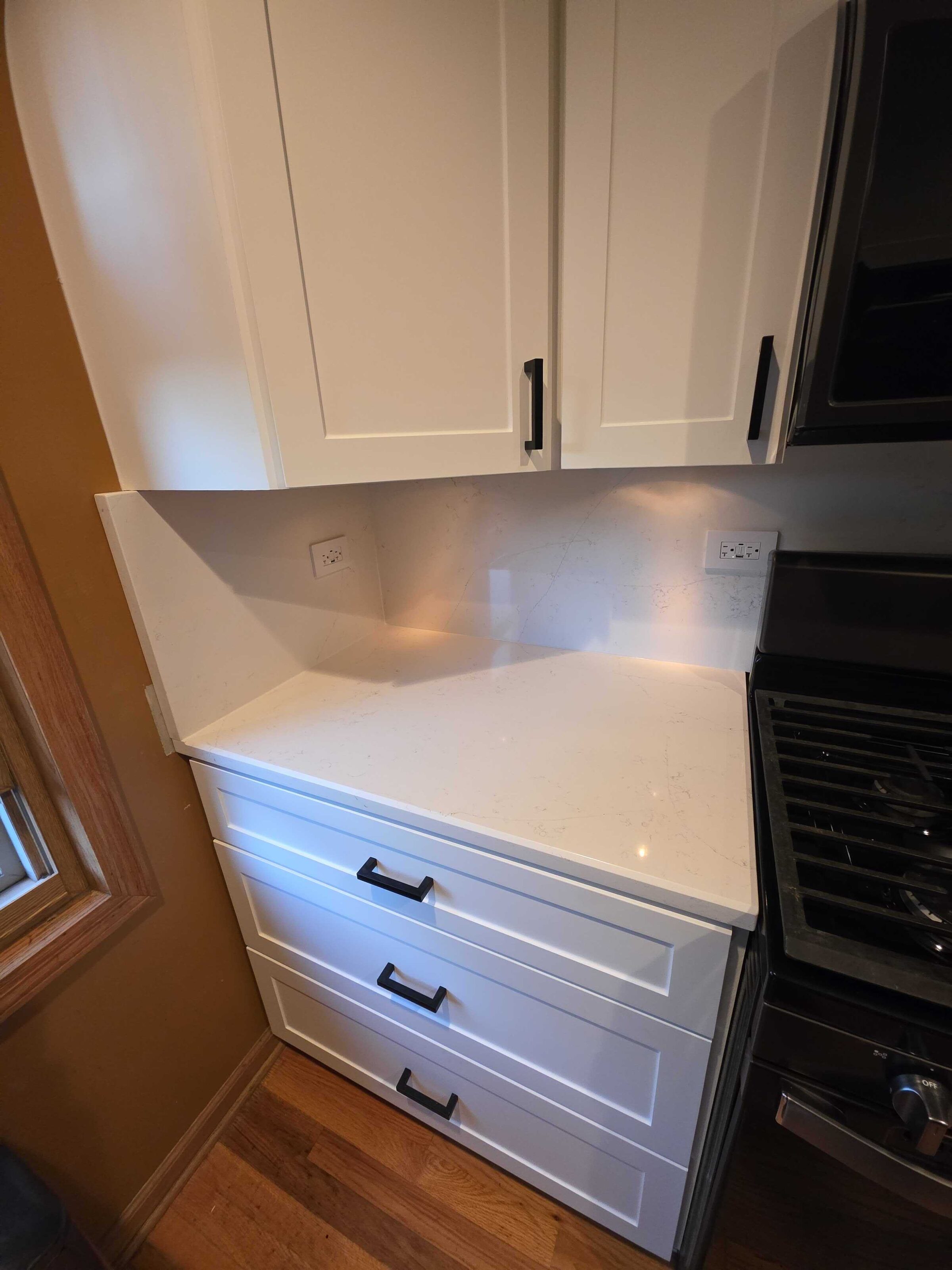 Quartz turning into the corner beside the range, white cabinets below